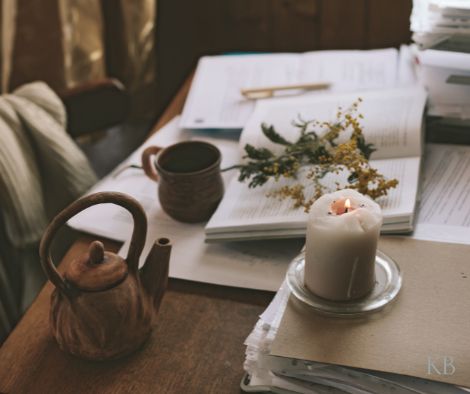 writing retreat. a notebook, candle, mug and teapot sitting on a wooden desk